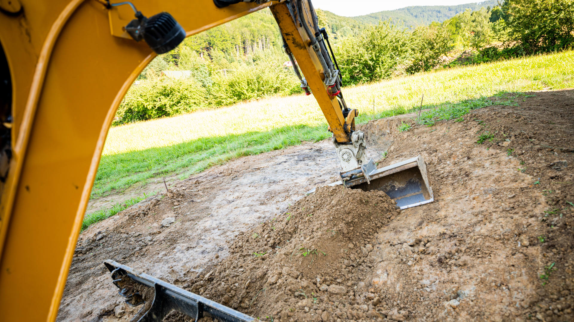 Mini excavator digging preparing ground under home garden